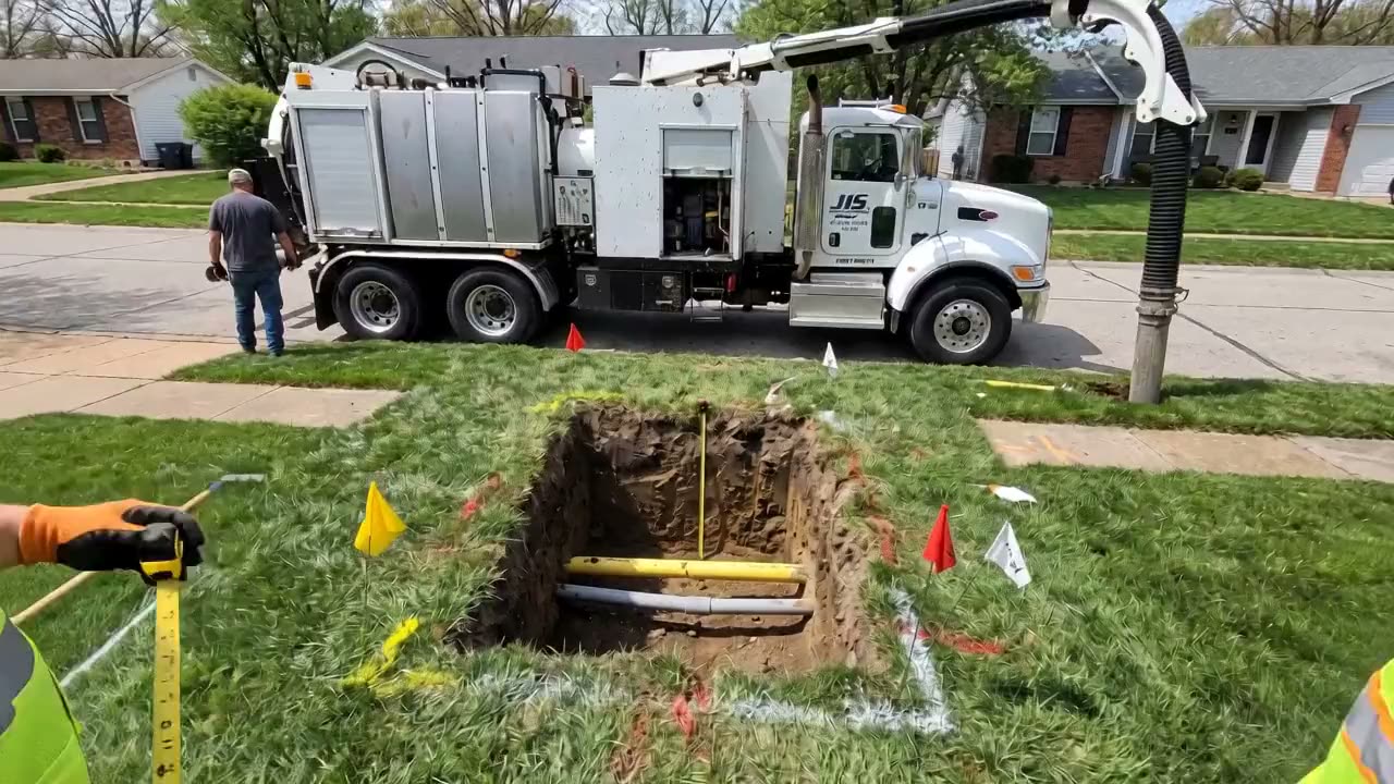 A clean square hole with a gas line and a conduit exposed, and a tape measure held down to them