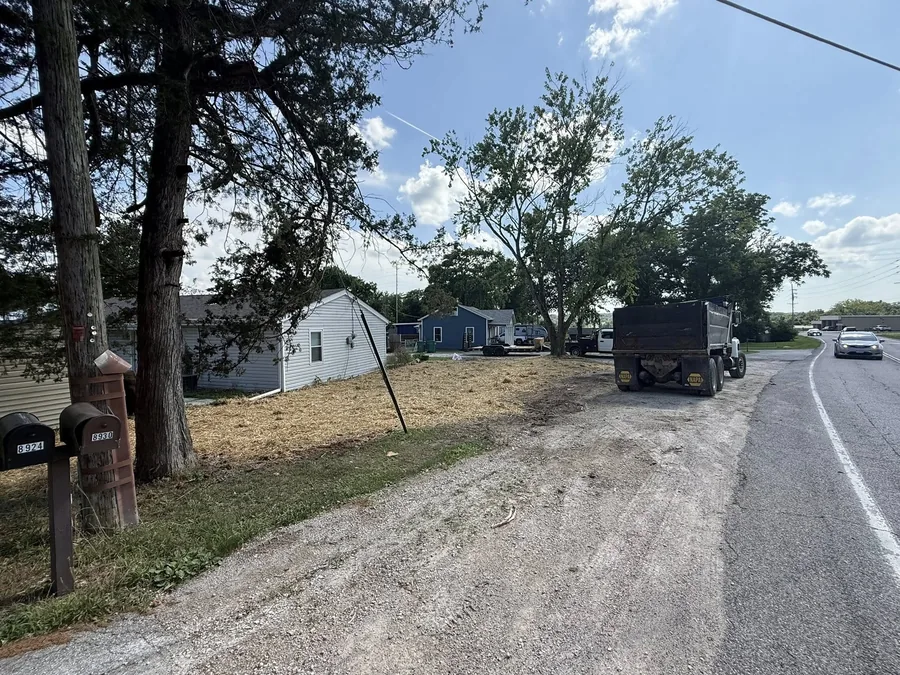The same lot after demolition, cleared and graded, with a dump truck at the road