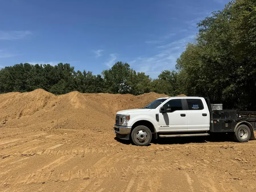 A pickup parked in front of a large pile of dirt