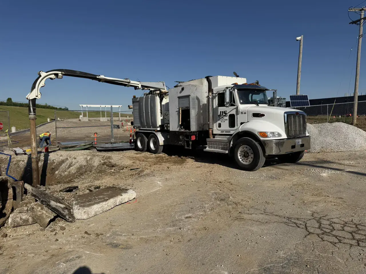 A J1S hydrovac truck with its boom lowered into an open excavation