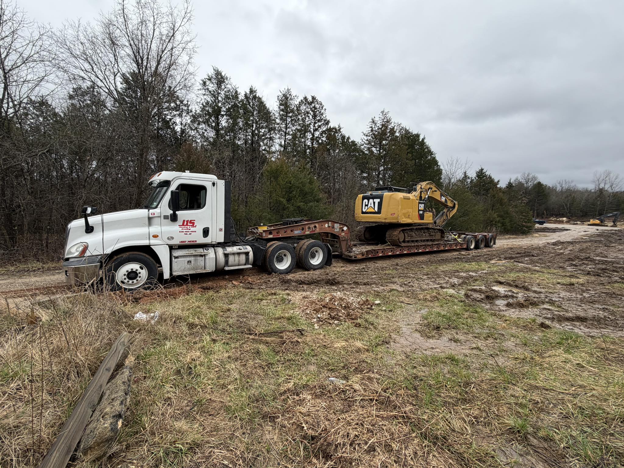 A J1S semi hauling an excavator on a lowboy trailer