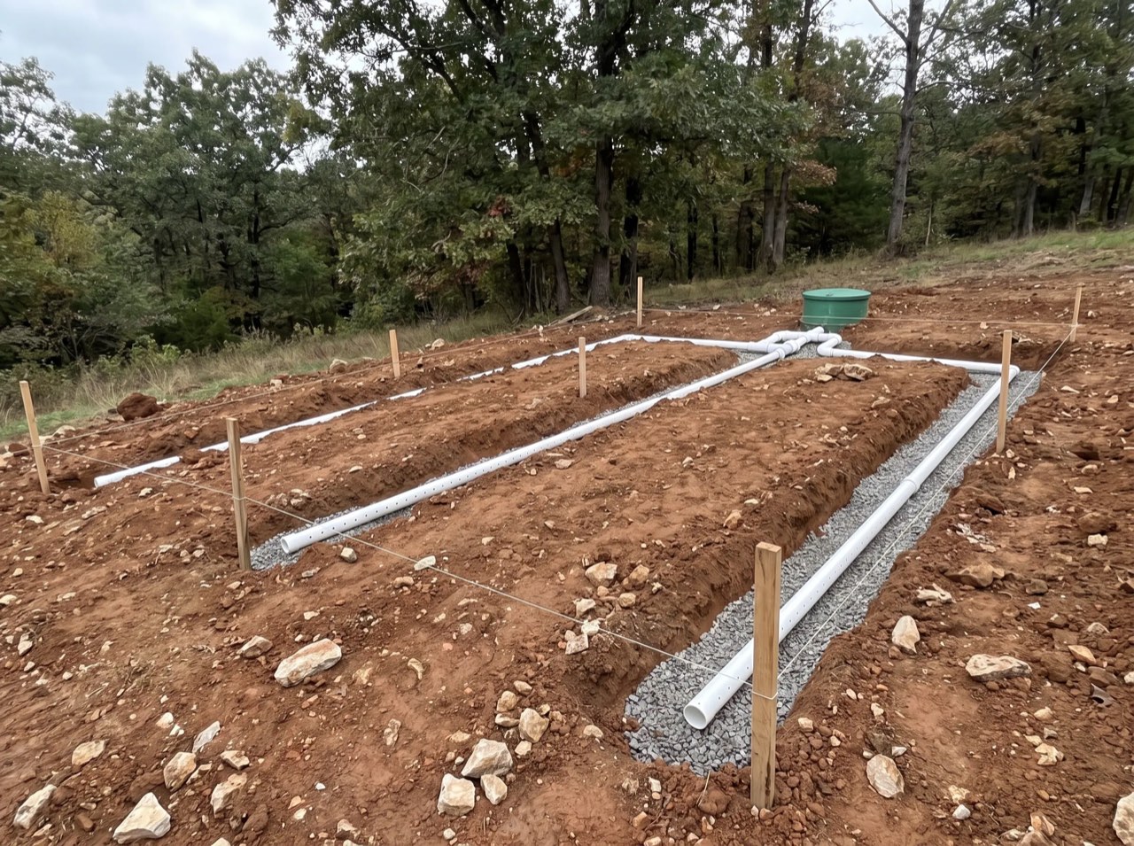Shallow, narrow trenches with small perforated pipes laid along a slope